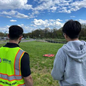 A student works with instructor to fly a drone.